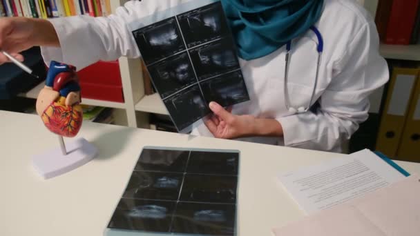 穆斯林心脏科医生坐在医院桌子旁边照X光的近景 — 图库视频影像