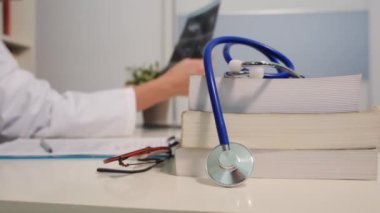 Steteskop manzarasını kapatın. Masada kitaplar ve hastanede arka plan üzerinde çalışan kadın doktor.