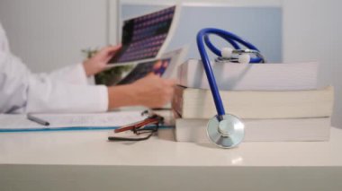 Steteskop manzarasını kapatın. Masada kitaplar ve hastanede arka plan üzerinde çalışan kadın doktor.