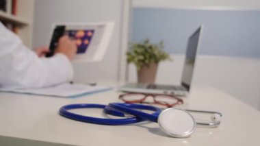 Masadaki steteskopun ve hastanedeki arka plandaki kadın doktorun görüntüsünü kapat.