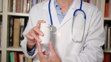 Yakın plan kadın doktor hastanede beyaz önlük giyiyor ve elinde haplar var.