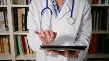 Kadın doktor hastanede beyaz önlük giyer ve tablet kullanır.