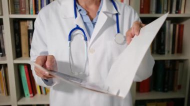 Yakın plan kadın doktor hastanede beyaz önlük giyer ve dosyada belgeler, teşhisler, reçeteler olur.