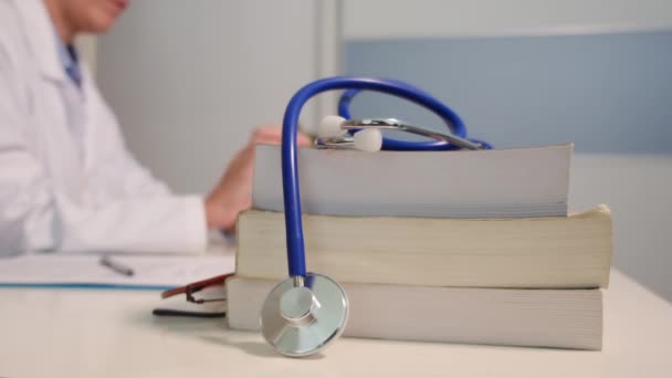 Närbild Stetoskop Med Böcker Bordet Och Kvinnlig Läkare Med Smartphone — Stockvideo