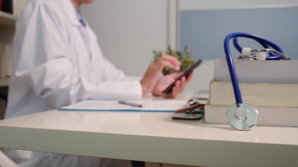 Vista Perto Estetoscópio Com Livros Mesa Médico Feminino Usando Smartphone — Vídeo de Stock