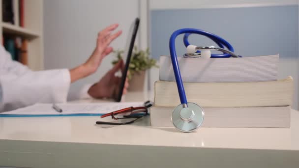 在医院背景下使用平板电脑与桌上书籍和女医生近距离接触听诊器 — 图库视频影像