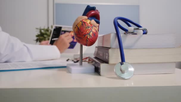 Προβολή Από Κοντά Του Καρδιολόγου Που Κάθεται Στο Τραπέζι Του — Αρχείο Βίντεο