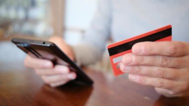 Akıllı telefon ve kredi kartı tutan ve evde online alışveriş yapan kadınları kapatın. Bankacılık, çevrimiçi alışveriş ve yaşam tarzı kavramı.