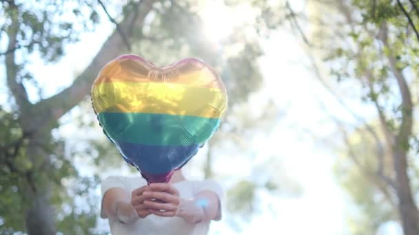 一种心形气球 颜色为Lgbtq 骄傲旗 由一个人持有 太阳光象征着平等 性自由 性别尊重和包容 — 图库视频影像