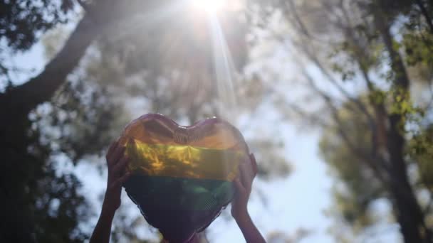一种心形气球 颜色为Lgbtq 骄傲旗 由一个人持有 太阳光象征着平等 性自由 性别尊重和包容 — 图库视频影像