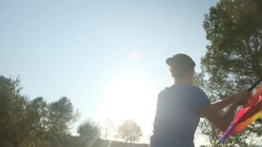 Gün batımında dalgalanan LGBTQ + bayrağıyla yalnız genç bir kadın. Eşitlik, eşitlik, dahil etme, LGBTQ konsepti. Aşk aşktır, ayrımcılık yok, özgürlüğe evet