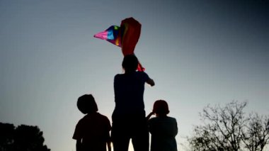 Anne ve iki çocuk gün batımında bir dağın tepesinde LGBTQ + bayrağı sallıyorlar. Aile, çeşitlilik, kapsama ve eşitlik kavramı. Gurur, lezbiyen anne ve çocuklar. Aşk aşktır.
