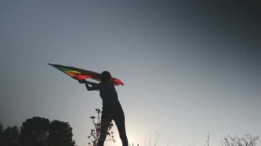 Gün batımında dalgalanan LGBTQ + bayrağıyla yalnız genç bir kadın. Eşitlik, eşitlik, dahil etme, LGBTQ konsepti. Aşk aşktır, ayrımcılık yok, özgürlüğe evet