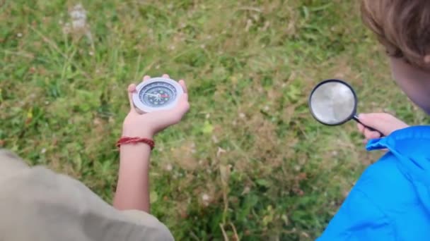 コンパスでガラスと弟を拡大する男の子 — ストック動画