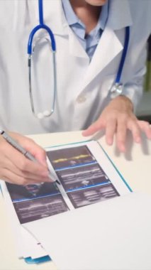 Steteskoplu genç bayan doktor ultrasonu inceliyor.