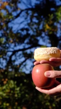 Anne ve oğlunun elleri meyve ve endüstriyel hamur işleri arasında seçim yapıyor. Sağlıklı meyve ve abur cubur arasında seçim yapmak zararlı beslenme, diyet konsepti yoluyla yararlı. Gıda eğitimi 