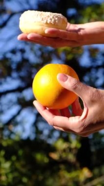 Anne ve oğlunun elleri meyve ve endüstriyel hamur işleri arasında seçim yapıyor. Sağlıklı meyve ve abur cubur arasında seçim yapmak zararlı beslenme, diyet konsepti yoluyla yararlı. Gıda eğitimi 