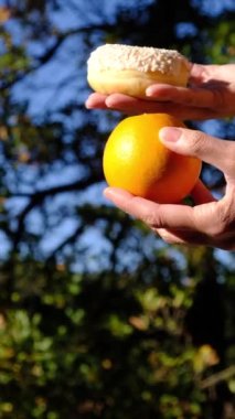 Anne ve oğlunun elleri meyve ve endüstriyel hamur işleri arasında seçim yapıyor. Sağlıklı meyve ve abur cubur arasında seçim yapmak zararlı beslenme, diyet konsepti yoluyla yararlı. Gıda eğitimi 