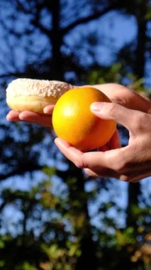 Anne ve oğlunun elleri meyve ve endüstriyel hamur işleri arasında seçim yapıyor. Sağlıklı meyve ve abur cubur arasında seçim yapmak zararlı beslenme, diyet konsepti yoluyla yararlı. Gıda eğitimi 