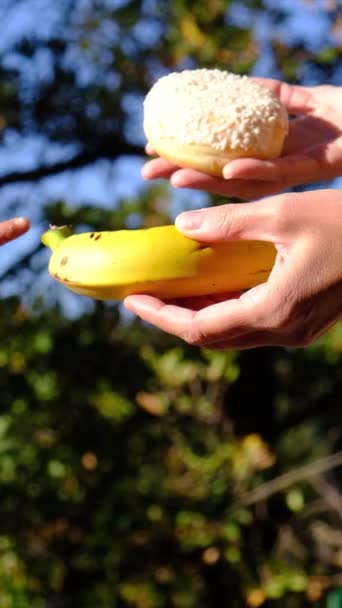 果物と工業用ペストリーの間で選択する母と息子の手 ドーナツ 有害な栄養 食事の概念を介して有用な健康なフルーツとジャンクフードの間で選択します フード教育 — ストック動画