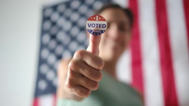 今日投票した女性は アメリカの国旗の背景に親指のバッジ — ストック動画