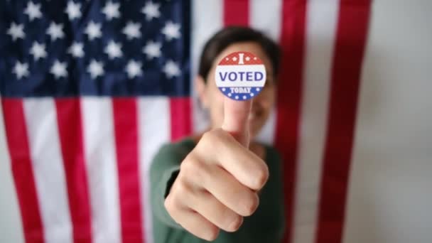 今日投票した女性は アメリカの国旗の背景に親指のバッジ — ストック動画