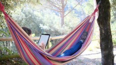 Hamakta tabletli genç bir kadın. 
