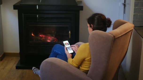 在壁炉边拿着智能手机的女人 — 图库视频影像