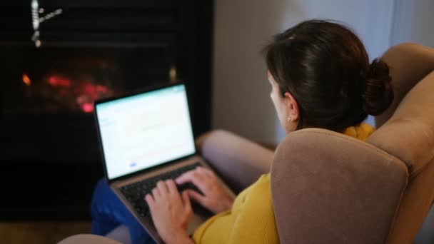 暖炉の近くでノートパソコンを使っている女性 — ストック動画