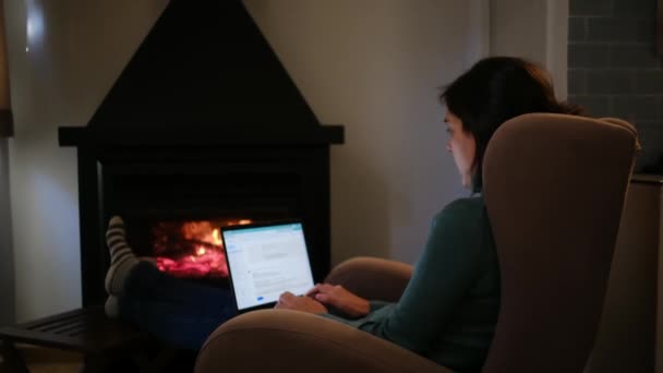 暖炉の近くでノートパソコンを使っている女性 — ストック動画