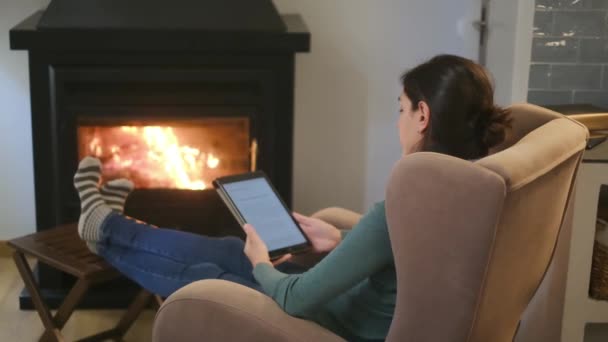 暖炉の近くでタブレットコンピュータを使用している女性 — ストック動画
