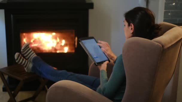 暖炉の近くでタブレットコンピュータを使用している女性 — ストック動画
