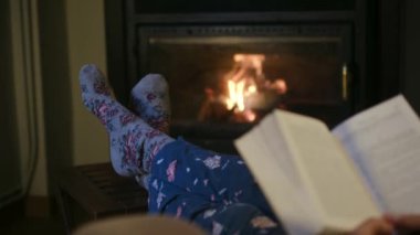 Şöminenin yanında kitap okuyan kadın.