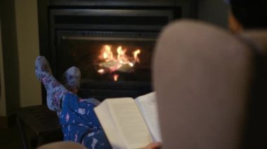 Şöminenin yanında kitap okuyan kadın.