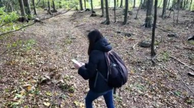 Ormanda akıllı telefonlu bir kadın doğa yürüyüşçüsü. 