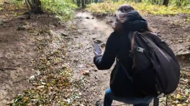 Ormanda akıllı telefonlu bir kadın doğa yürüyüşçüsü. 