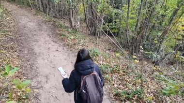Ormanda akıllı telefonlu bir kadın doğa yürüyüşçüsü. 