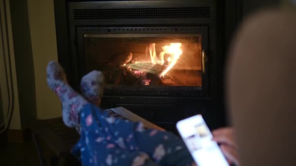 Sıcak Çoraplı Şöminenin Yanında Akıllı Telefonu Olan Bir Kadın — Stok video