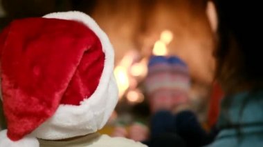 Annesi şöminenin başında oturan çocuk.