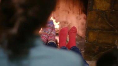 Sıcak çoraplı çocuklar şöminenin başında oturuyorlar.