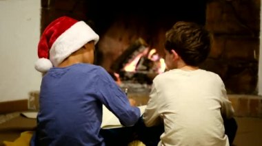 Çocuklar Noel 'i şömineyle kutluyor. Çocuk Noel Baba 'ya mektup yazıyor.