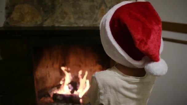 Chłopiec Kapeluszu Świętego Mikołaja Pobliżu Kominka — Wideo stockowe