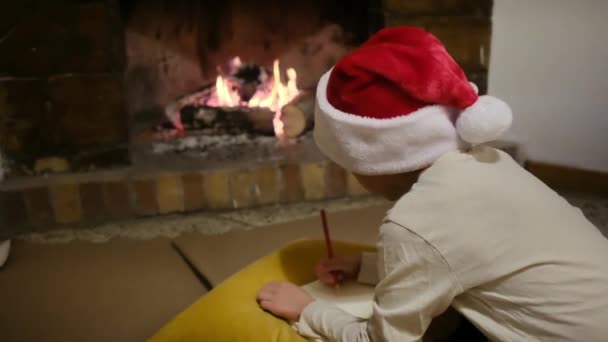 Junge Mit Weihnachtsmann Hut Schreibt Brief Weihnachtsmann Kamin — Stockvideo