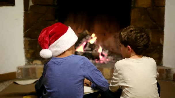 孩子们在壁炉边庆祝圣诞节 男孩写信给桑塔 — 图库视频影像