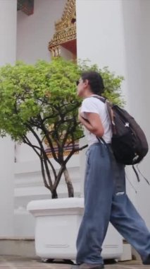 Sırt çantalı kadın gezginin arkasında Güneydoğu Asya 'daki Budist kültürünün cazibe mimari geçidinde yürüyor.