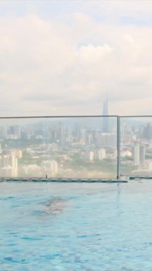 şehir silueti üzerinde sonsuz havuzda yüzen seyahat eden bir kadın. 