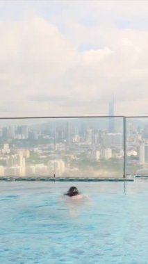 şehir silueti üzerinde sonsuz havuzda yüzen seyahat eden bir kadın. 