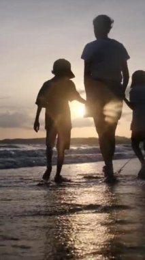 Aile bağının yürek ısıtan özünü bir annenin ve oğullarının sakin bir sahilde büyüleyici bir gün batımının arka planında el ele tutuşmaları gibi yaşayın.