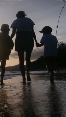 Aile bağının yürek ısıtan özünü bir annenin ve oğullarının sakin bir sahilde büyüleyici bir gün batımının arka planında el ele tutuşmaları gibi yaşayın.