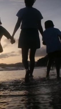 Aile bağının yürek ısıtan özünü bir annenin ve oğullarının sakin bir sahilde büyüleyici bir gün batımının arka planında el ele tutuşmaları gibi yaşayın.
